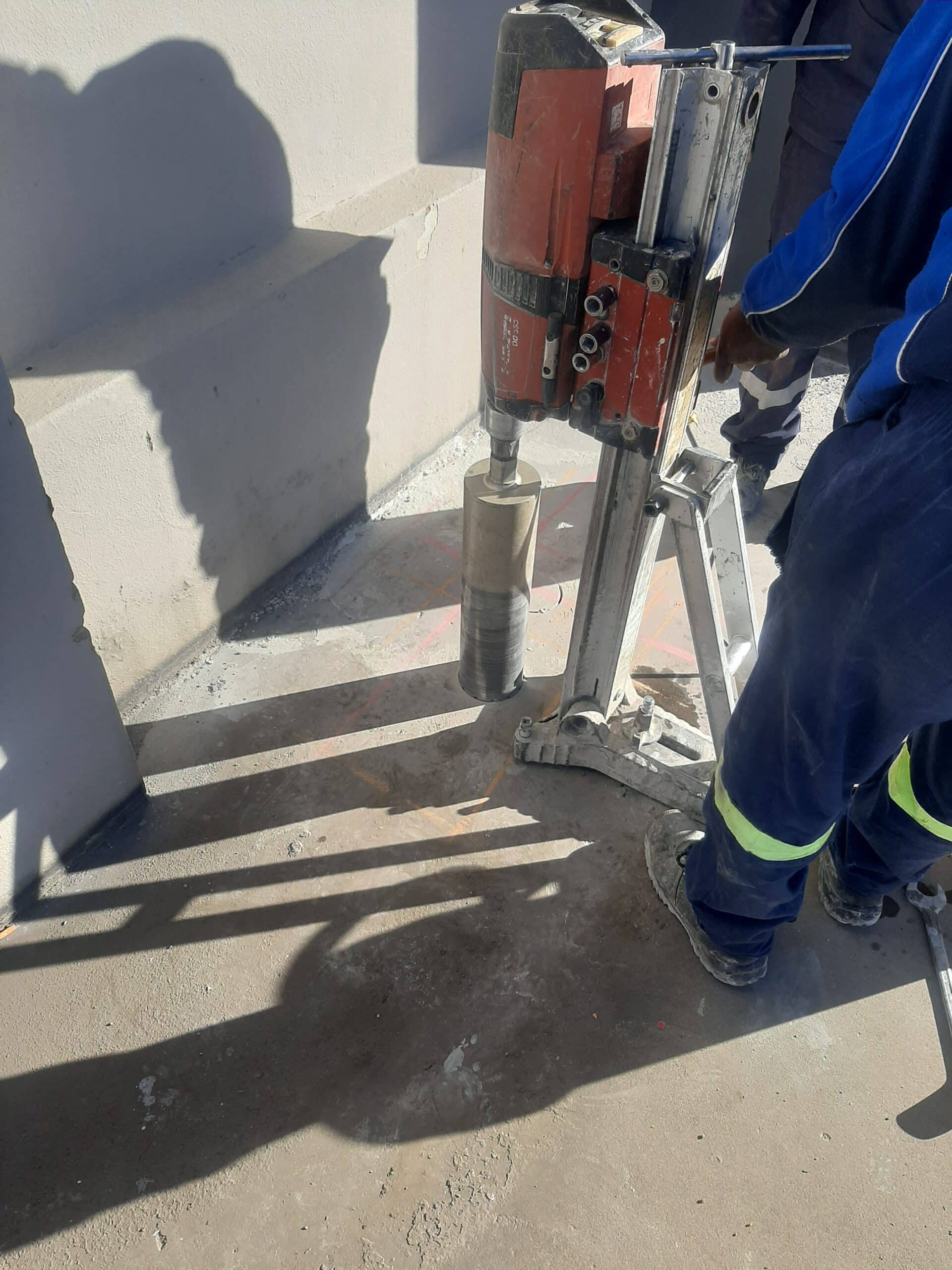 Hilti DD 350 core drilling machine mounted on a rig, drilling a core hole into a concrete slab on site