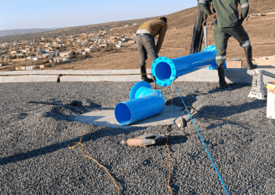 Workers installing blue pipework on the roof of the Moloto reservoir during the infrastructure project