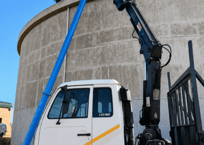 Truck-mounted equipment and blue pipework beside the concrete Moloto water reservoir