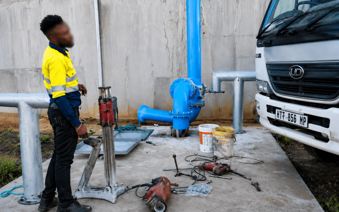 Vus Core Drilling technician at a concrete drilling worksite with industrial pipework and drilling equipment
